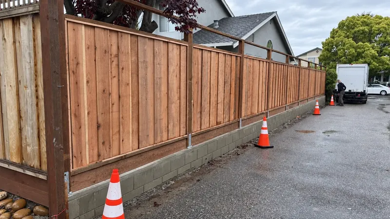 Low concrete block retaining wall beneath a wooden fence